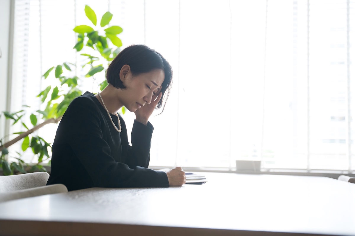 葬儀後に納骨について静かな室内空間で椅子に座り一人で考え込む後ろ姿